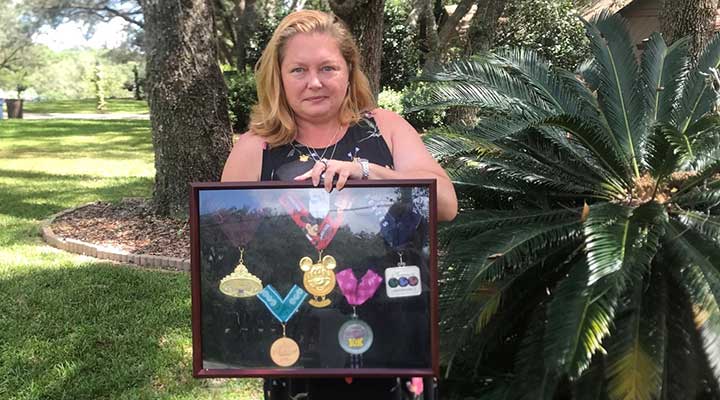 public storage facilities manager michelle holds up past marathon medal